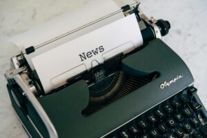 Decorative image of an antique style type-writer with a paper labeled "News"